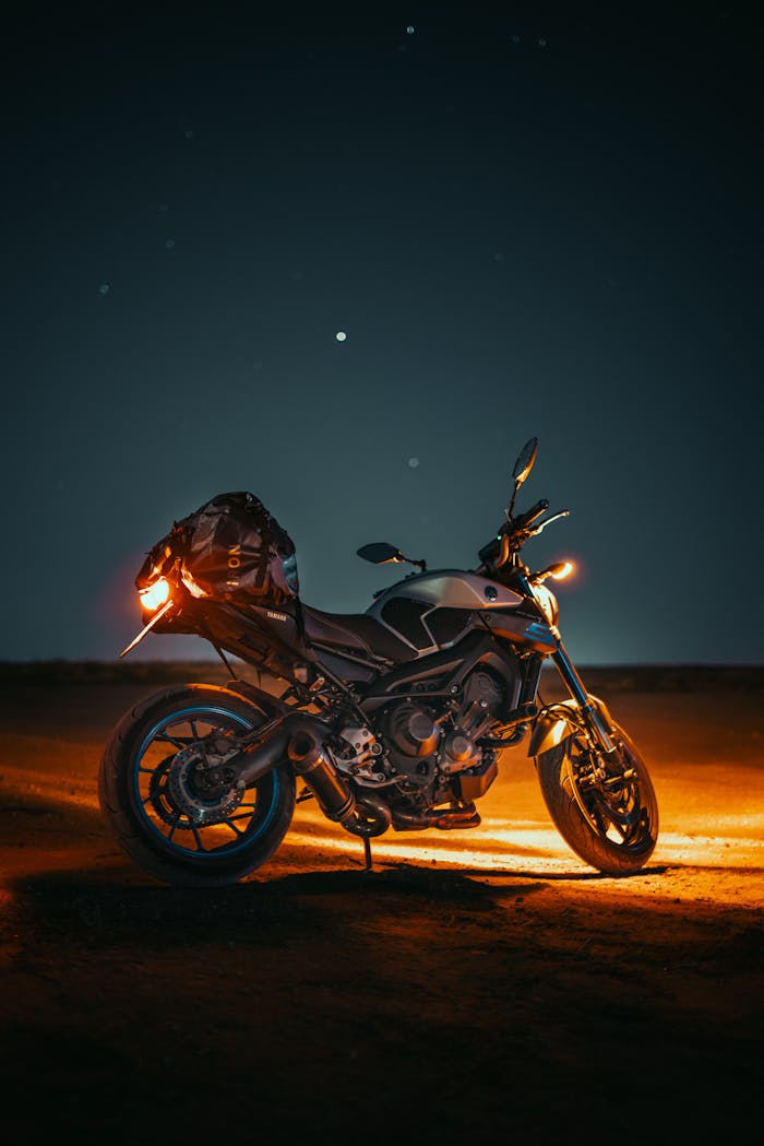 Stunning nighttime shot of a motorbike highlighted under the stars in a desert landscape.